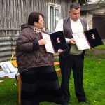 Bibliotekininkė Benita ir Rolandas Jankauskas rankose laiko Rolando močiutei Kotrynai Šulcienei įteiktą Žūvančiųjų gelbėjimo kryžių.
